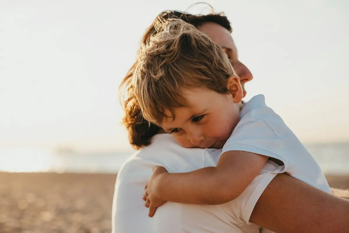 Pai abraçando o filho pequeno na praia ao entardecer